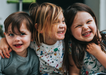 Staatsbürgerschaft Österreich: drei Kinder sitzen auf Stufe und umarmen sich