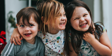 Staatsbürgerschaft Österreich: drei Kinder sitzen auf Stufe und umarmen sich