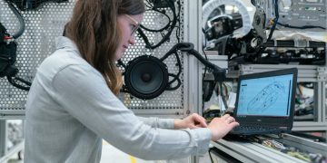 woman in white long sleeve shirt using black laptop computer