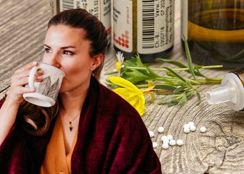 Frau trinkt eine Tasse Tee, Globuli im Hintergrund