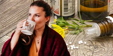 Frau trinkt eine Tasse Tee, Globuli im Hintergrund