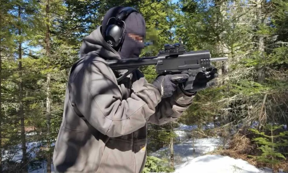 Auf dem Foto ist eine vermummte Person mit Gehörschutz und Handschuhen zu sehen, die in einem verschneiten Wald eine 3D-gedruckte Schusswaffe („Ghost Gun“) im Anschlag hält. Foto: JStark1809 / Deterrence Dispensed (CC BY 4.0)