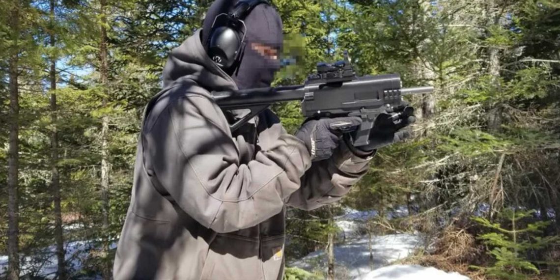 Auf dem Foto ist eine vermummte Person mit Gehörschutz und Handschuhen zu sehen, die in einem verschneiten Wald eine 3D-gedruckte Schusswaffe („Ghost Gun“) im Anschlag hält. Foto: JStark1809 / Deterrence Dispensed (CC BY 4.0)