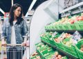Eine Frau mit Einkaufswagen betrachtet in einem Supermarkt frisches Obst. (Foto: Unsplash)