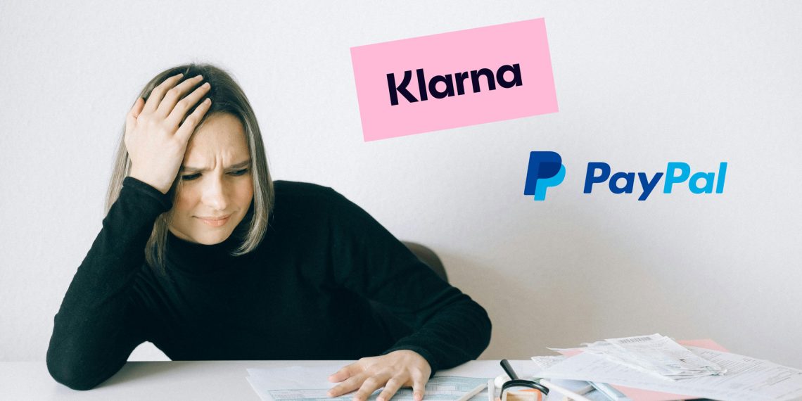 Frau sitzt am Tisch und hält sich mit genervtem Gesichtsausdruck den Kopf, vor ihr liegen Rechnungen und Papierkram. Logos von Klarna und PayPal