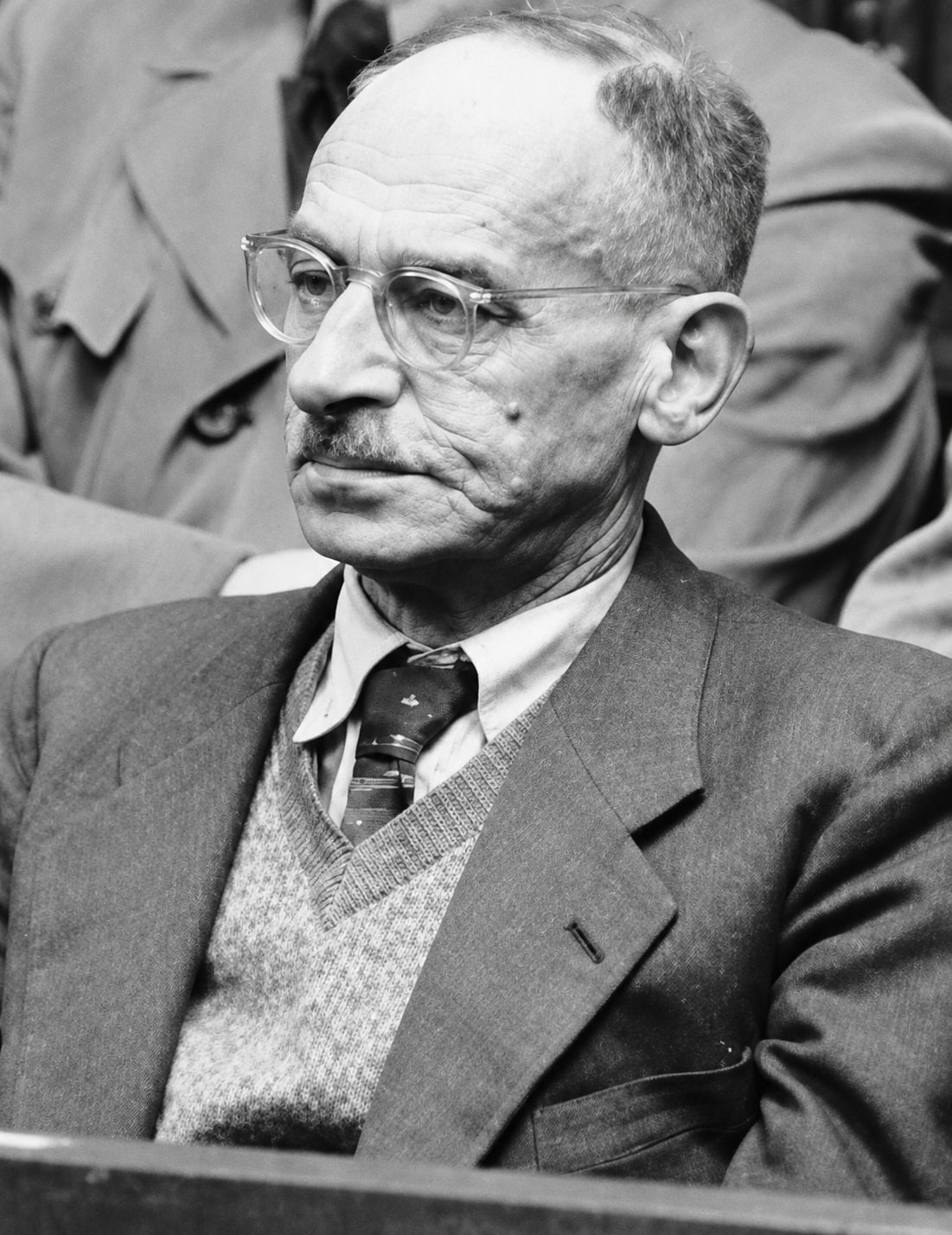 Wilhelm Keppler, Unternehmer, NSDAP-Mitglied und später SS-Obergruppenführer, gründete 1932 auf Hitlers Auftrag den „Keppler-Kreis“. Der Kreis aus rund 20 Wirtschaftsvertretern sollte ein NS-Wirtschaftsprogramm ausarbeiten, Industrielle an Hitler binden und seine Ernennung zum Reichskanzler fördern. Hitler fürchtete nämlich, die bisherigen Wirtschaftsexperten der Partei würden mit sozialistischen Ideen großindustrielle Spender abschrecken. Vom Keppler-Kreis ging wohl auch das Konzept zur „Machtergreifung“ aus, also der Plan, nach erfolgreicher Wahl über Ermächtigungsgesetze und folglich ohne ein Parlament zu regieren. (Im Bild: Wilhelm Keppler auf der Anklagebank im Nürnberger Wilhelmstraßen-Prozess, Quelle: Wikipedia/gemeinfrei, mit KI optimiert)